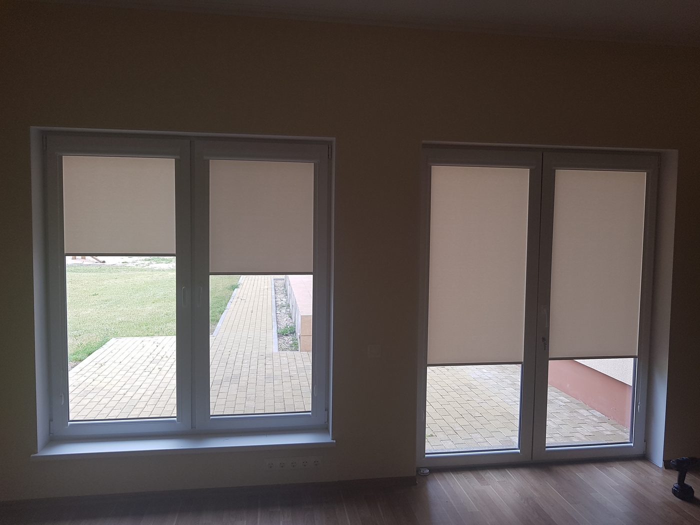 Baltas kasešu žalūzijas viesistabas logā un balkona durvīs
