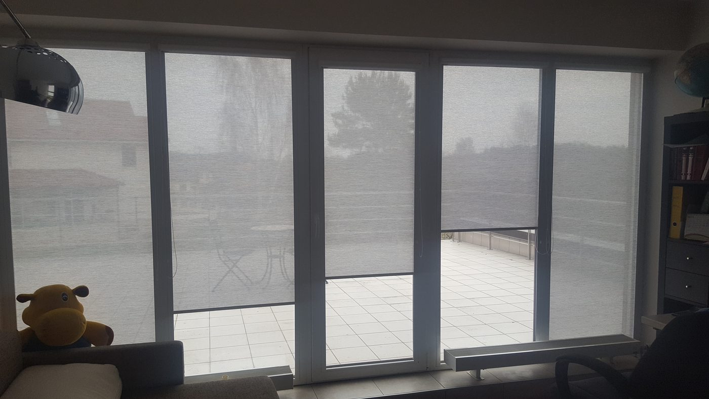 Pelēkas screen kasešu žalūzijas uz panorāmas durvīm ar izeju uz terasi