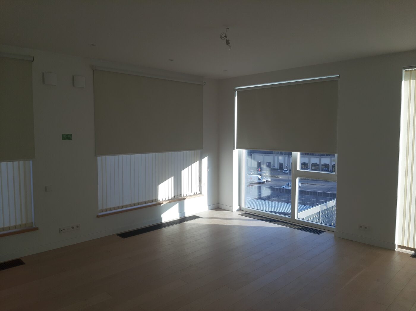 Bēšas rullo žalūzijas uz dzīvokļa panorāmas durvīm un logiem