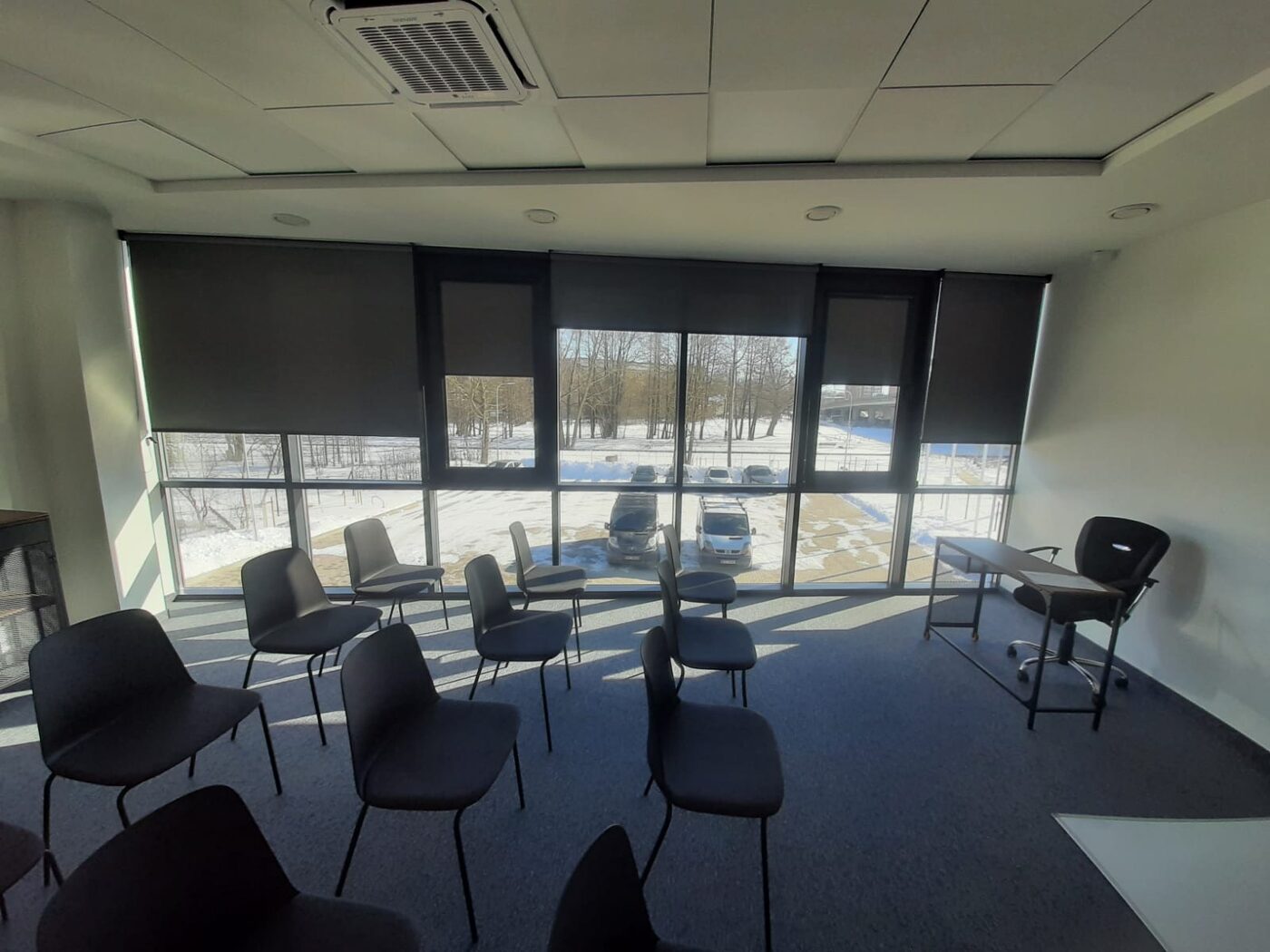 Tumšas screen rullo žalūzijas konferenču zālē — aizsardzība pret sauli bez aptumšošanas