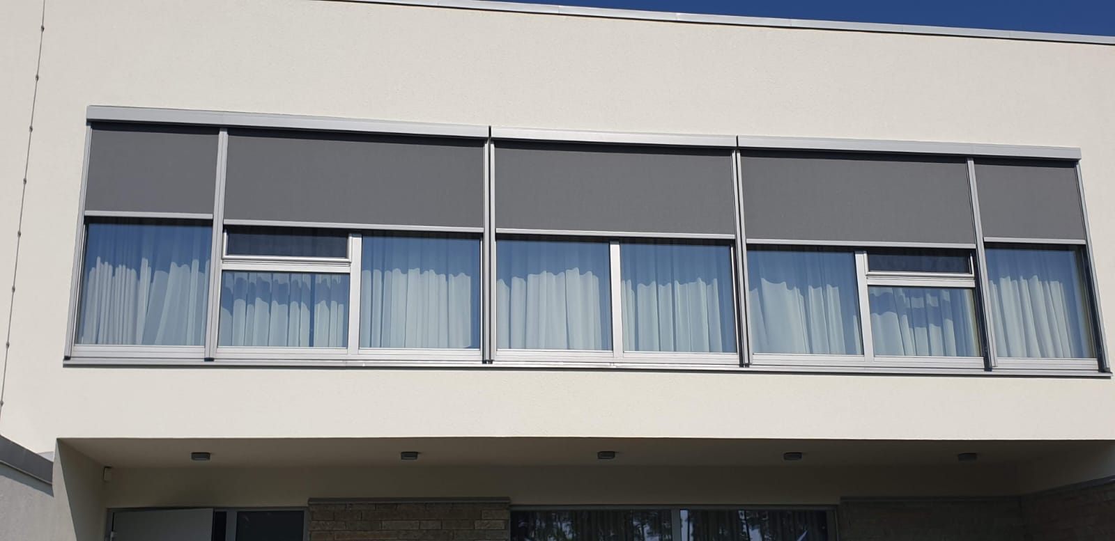 Graue Fassaden-Zip-Screens, ein Teil der Behänge ist hochgefahren — FENSTORA, Riga