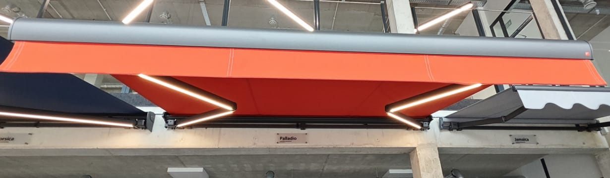 Izvelkama markīze ar sarkanu audumu un LED apgaismojumu sviras, skats no apakšas — FENSTORA, Rīga