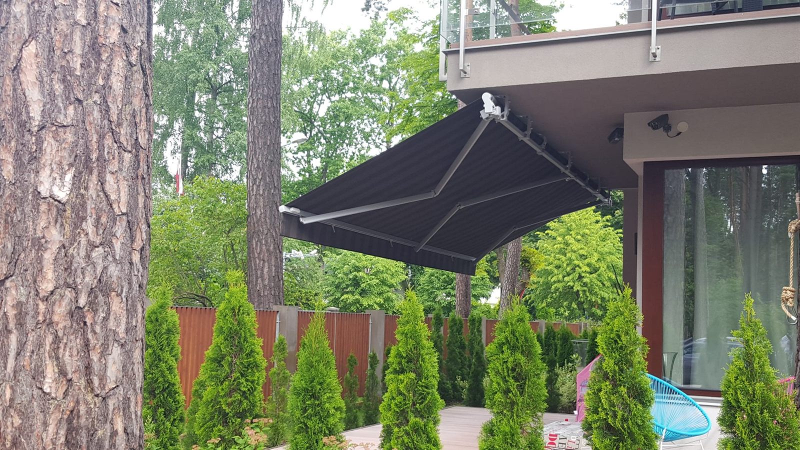Antracīta izvelkama markīze pie baseina starp priedēm zemesgabalā — FENSTORA, Rīga